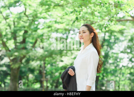 Jeune japonaise entouré de verdure dans un parc de la ville Banque D'Images