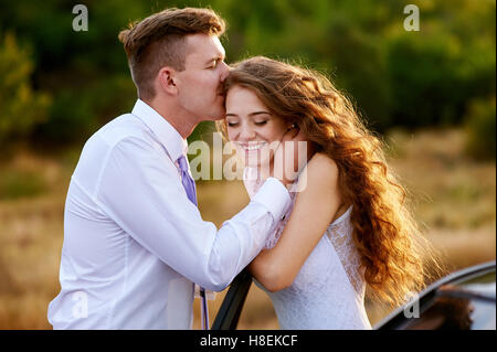 Groom kissing bride dans la tête au mariage à pied Banque D'Images