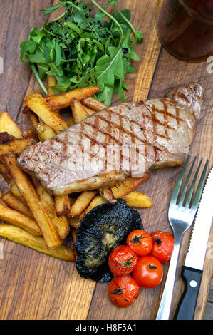 Steak et frites avec les champignons et les tomates servi sur un plateau en bois. une cuisine britannique de sécurité alimentaire Banque D'Images