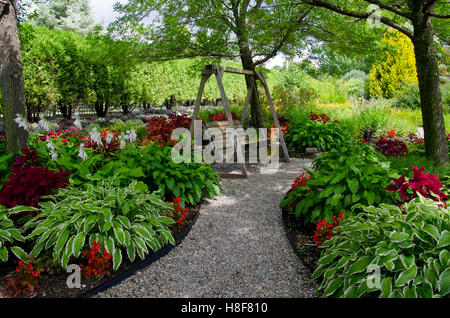 Balançoire en bois horizontales à Pineland jardin avec des hostas et coléus le long sentier ombragé, Maine, USA Banque D'Images