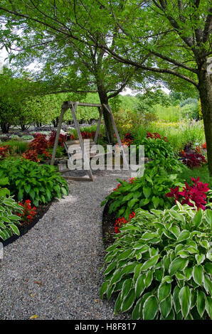 Une balançoire en bois vertical à Pineland Botanical garden sur chemin avec fleurs et hostas, New Gloucester, Maine, USA Banque D'Images