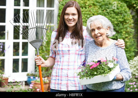 Teenage Granddaughter aider grand-mère à jardin Banque D'Images