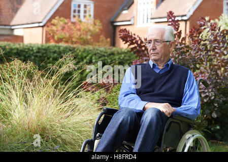 Déprimé Senior Man Sitting Outdoors In Wheelchair Banque D'Images