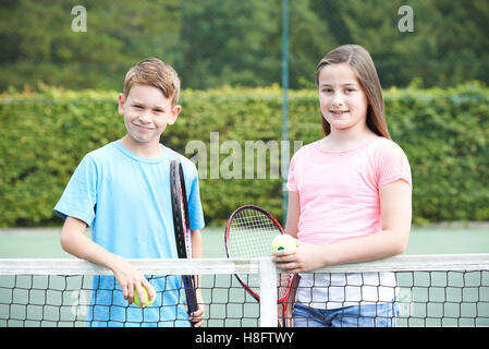 Portrait de garçon et fille jouer au tennis ensemble Banque D'Images