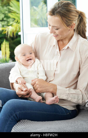 Grand-mère assise sur un canapé avec bébé fille Banque D'Images