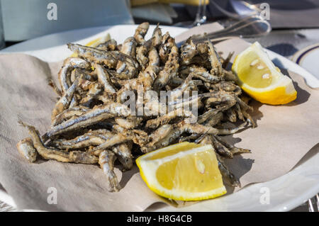 Assiette de petits anchois (engraulis encrasicolus), frites, poissons entiers et servi avec du citron. Plat typique de la Ligurie, Italie. Banque D'Images