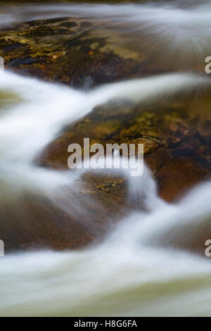 De l'eau brouillée circulant sur une petite chute. Banque D'Images