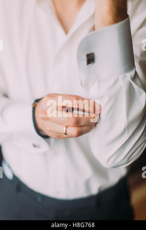 Jeune élégante mode homme en chemise blanche à fixer son cufflinks Banque D'Images