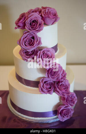 Un gâteau de mariage blanc multi de niveau sur la base et des fleurs roses sur le dessus Banque D'Images
