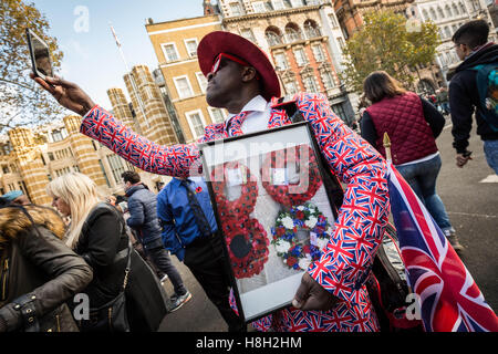 Londres, Royaume-Uni. 13 novembre, 2016. Un homme vêtu de vêtements de l'union, se tenant une photo encadrée de guirlandes de pavot prend un téléphone mobile photo du cénotaphe de Whitehall, Londres pendant la cérémonie du souvenir memorial dimanche hommages. Crédit : Guy Josse/Alamy Live News Banque D'Images