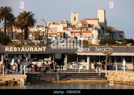 Frankreich, Cote d Azur, Strandrestaurant mit dem Altsttadt von Antibes mit der château Grimaldi. Banque D'Images