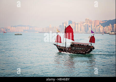 Jonque Chinoise Traditionnelle avec Red Sails dans le port de Victoria de Hong Kong au crépuscule Banque D'Images