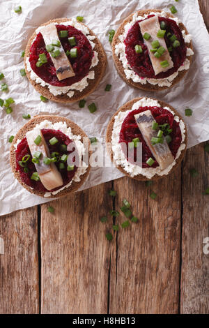 Sandwich scandinave avec du hareng, betterave et fromage à la crème sur la table. vertical Vue de dessus Banque D'Images