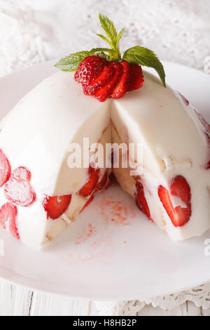 Gâteau au fromage aux fraises décoré de menthe et de baies fraîches close up sur une plaque verticale. Banque D'Images