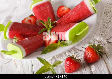 Popsicle fraise fait maison sur un bâton sur une plaque horizontale de près. Banque D'Images