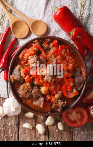 Agneau mijoté lentement avec l'oignon, la tomate et le poivre close-up dans un bol sur la table. vertical Vue de dessus Banque D'Images