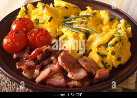 Oeufs brouillés à la ciboulette, bacon et les tomates sur une plaque horizontale. Banque D'Images