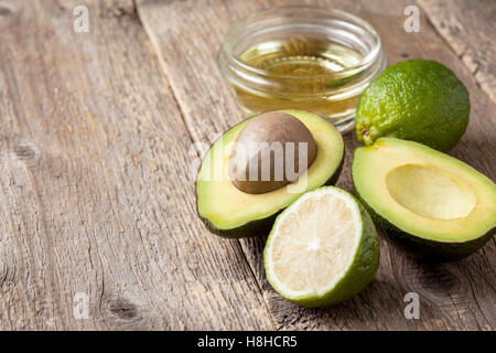 L'avocat, citron vert, huile sur table en bois ancien Banque D'Images