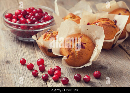 Muffins aux canneberges, les canneberges dans un bol en verre sur le vieux fond de bois Banque D'Images