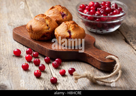 Muffins aux canneberges, les canneberges dans un bol en verre sur le vieux fond de bois Banque D'Images