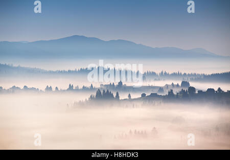 Matin brumeux de l'automne dans les montagnes des Carpates. Alpine Village sur les collines Banque D'Images