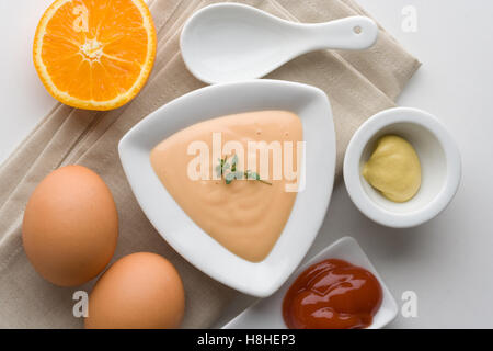 Sauce cocktail dans un bol blanc à l'orange, les œufs, le ketchup et la moutarde. Salade et vinaigrette de fruits de mer. Banque D'Images