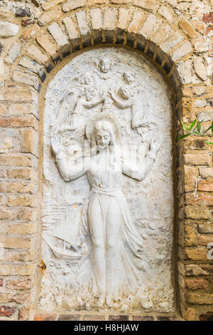 Bas-relief entouré de mur de brique représentant la Vierge Marie entourée par des anges. Banque D'Images