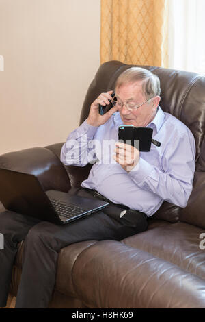 Shot verticale du pensionné à l'aide de dispositifs électroniques modernes comme l'ordinateur portable et téléphone mobile Banque D'Images