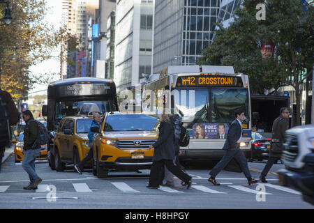 Les gens traversent la 42e rue en face de l'crosstown traffic pendant l'heure de pointe du matin dans la ville de New York. Banque D'Images