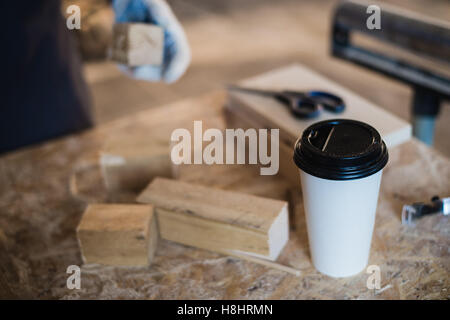 Menuiserie moderne avec lieu de travail comprimé, le café, les ciseaux et les pièces de bois sur la table, dans l'atelier Banque D'Images