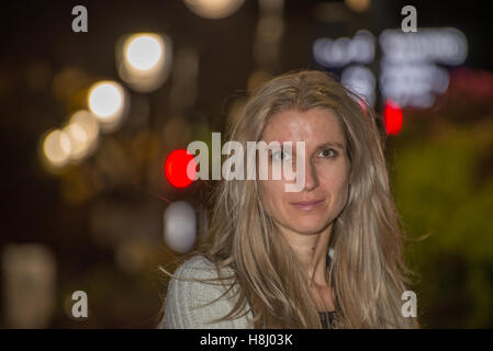 Jolie femme blonde dans la ville dans la nuit avec un arrière-plan flou Banque D'Images