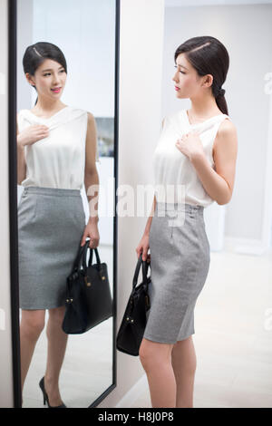 Jeune femme chinoise elle-même de l'examen in front of mirror Banque D'Images