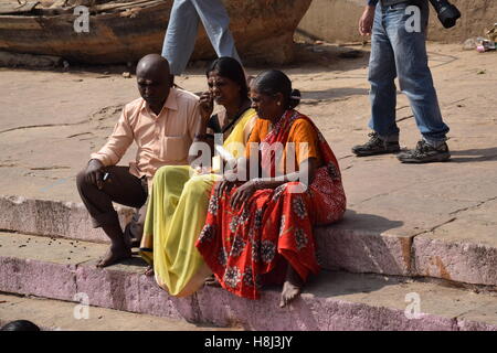 Trois indiens avec robes colorées assis sur les ghats de Varanasi, Uttar Pradesh, Inde Banque D'Images