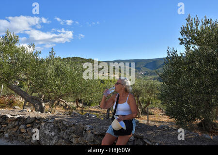 Les femmes assises sur un vieux mur de pierre de l'eau potable avec ciel bleu en arrière-plan, photo de l'île de Brac en Croatie. Banque D'Images