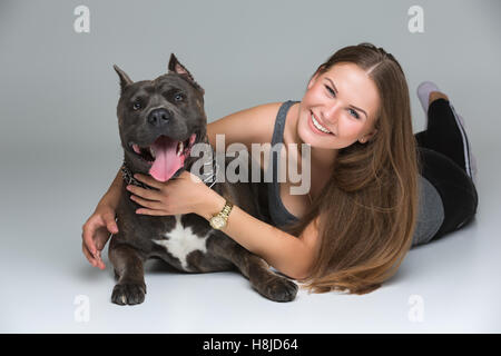 Belle fille avec Stafford Terrier gris Banque D'Images