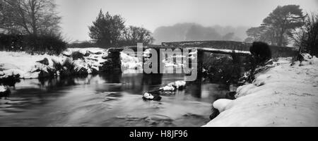 Deux ponts sur le Dartmoor en hiver avec un fond brumeux et les banques couvertes de neige et un froid de glace à l'Est de la rivière Dart. Banque D'Images