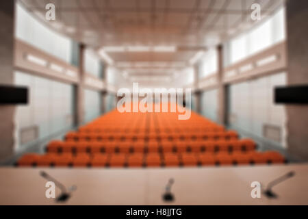 Flou abstrait tribune avec microphone et l'ordinateur dans la salle de conférence. Couleur Orange Banque D'Images