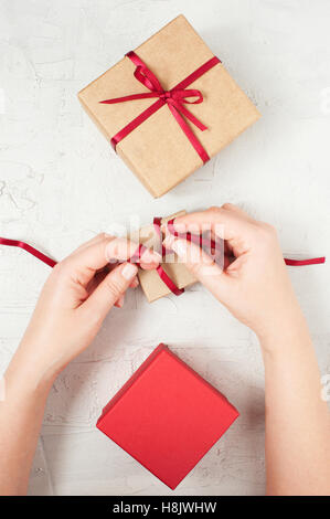 Woman's hands arc rouge noué sur la boîte-cadeau, tableau blanc Banque D'Images