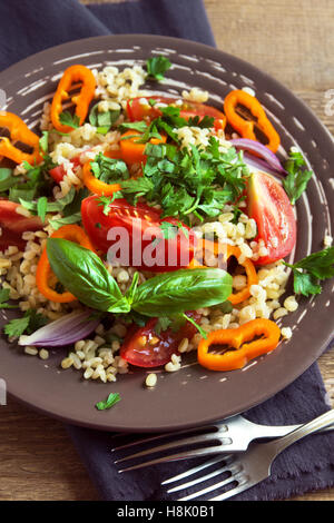 Produits bio frais et tomates Salade de couscous aux légumes et les verts - salade végétarienne saine sur plaque rustique close up Banque D'Images