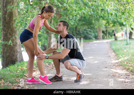 Aide à l'homme femme avec genou blessé lors de l'activité sportive Banque D'Images