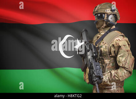 Soldat dans helmet holding machine gun avec drapeau national sur l'arrière-plan - Libye Banque D'Images