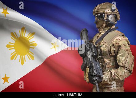 Soldat dans helmet holding machine gun avec drapeau national sur l'arrière-plan - Philippines Banque D'Images