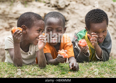 Meki Batu, Éthiopie - Les jeunes enfants de rire et de manger des tomates à la coopérative de producteurs de fruits et légumes à Meki Batu. Banque D'Images