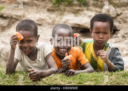 Meki Batu, Éthiopie - Les jeunes enfants de rire et de manger des tomates à la coopérative de producteurs de fruits et légumes à Meki Batu. Banque D'Images