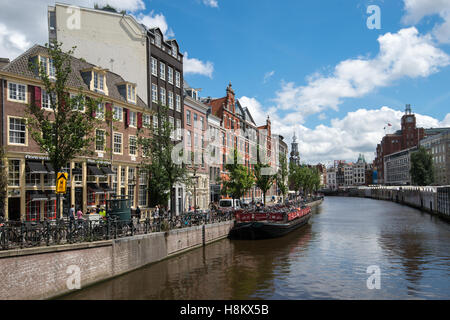 Amsterdam, Pays-Bas vue front de touristes marcher le long d'un canal à Amsterdam. Dans l'arrière-plan est la tour avec Banque D'Images