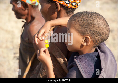 Portrait de San ou Bushman enfant jouant avec des fleurs d'Acacia Banque D'Images