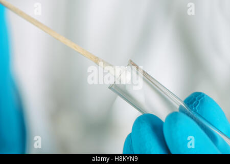 Coton-tige et tube à essai d'ADN, macro image d'équipements médicaux dans les mains de professionnels de la santé Banque D'Images