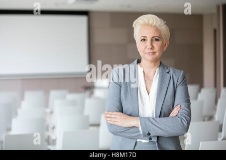 Portrait of confident businesswoman standing in salle de séminaire Banque D'Images