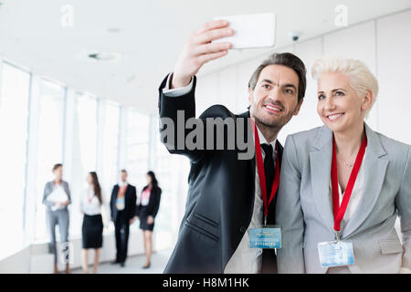 Les gens d'affaires prenant en selfies convention center avec des collègues en arrière-plan de marche Banque D'Images