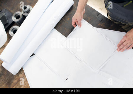 High angle view of young architect with blueprints à table dans l'industrie Banque D'Images